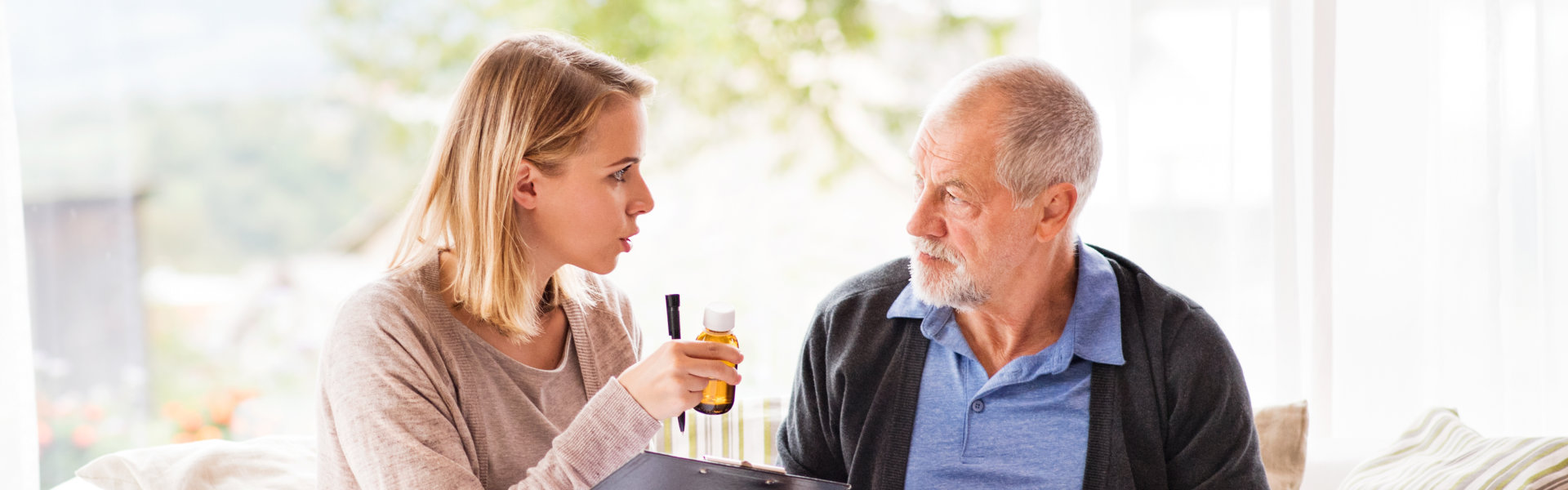 Health visitor and a senior man with tablet during home visit