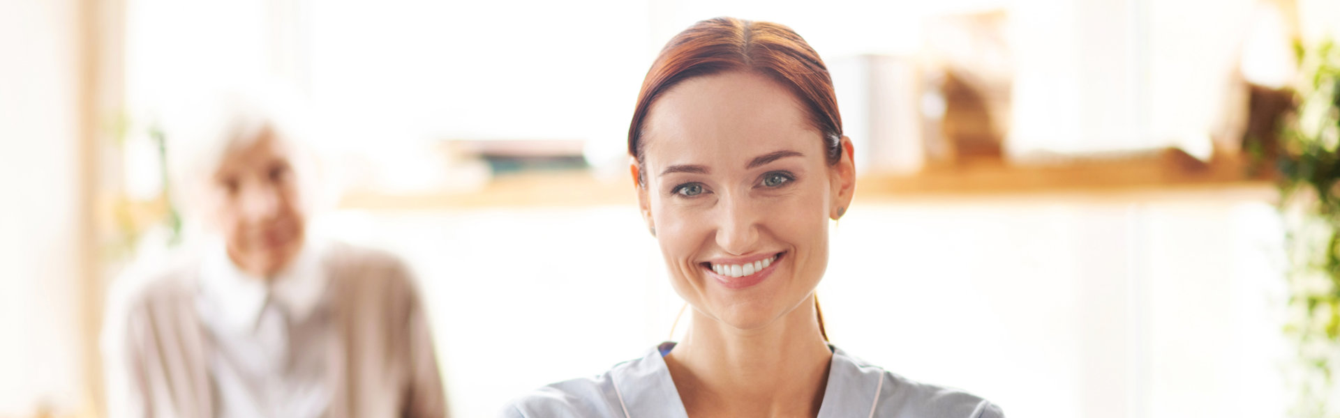 Cheerful caregiver wearing uniform holding packs of medication