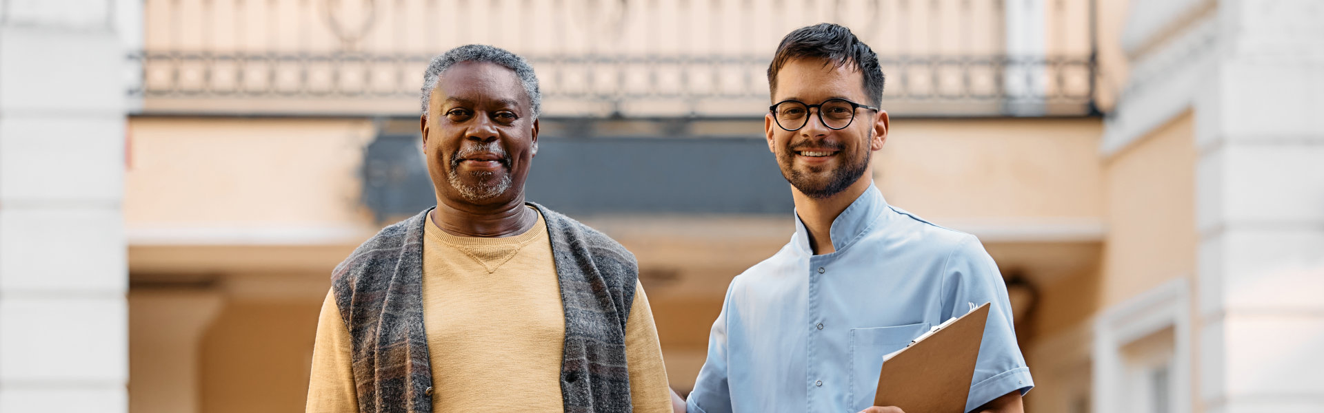 senior man and young caregiver looking at camera